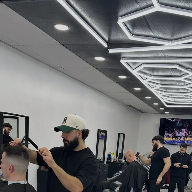 Barbers at work under the hexagon light ceiling